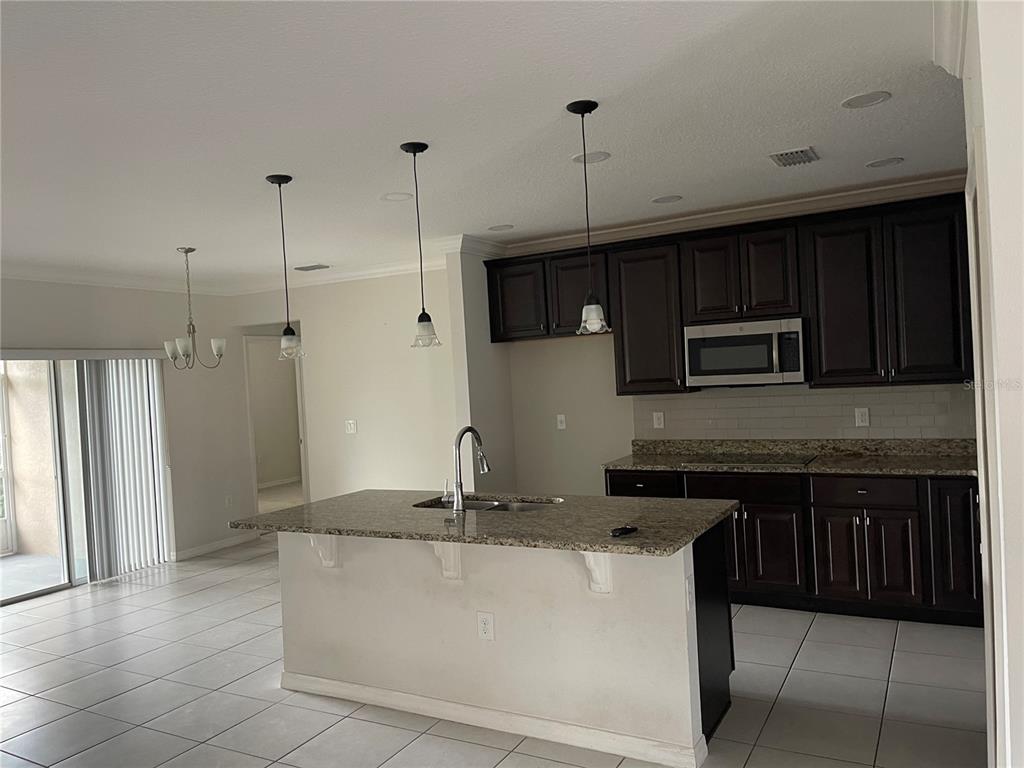 1312 Ralph Poe Drive Apopka, FL 32703 - Photo 9 of 14 a kitchen with kitchen island granite countertop a refrigerator a stove a microwave and a sink