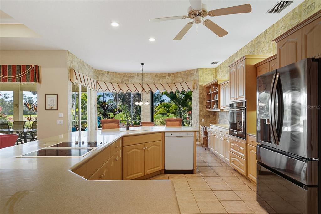 2116 Muskogee Trail Nokomis, FL 34275 - Photo 28 of 62 a kitchen with stainless steel appliances granite countertop a refrigerator a oven a sink with a dining table and chairs