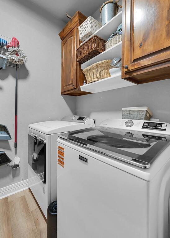 550 Hunton Lane Robinson, TX 76706 - Photo 28 of 35 Laundry room with washing machine and dryer, cabinet space, and light wood-type flooring