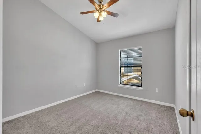 an empty room with windows and ceiling fan