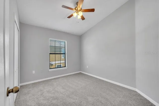 an empty room with windows and fan