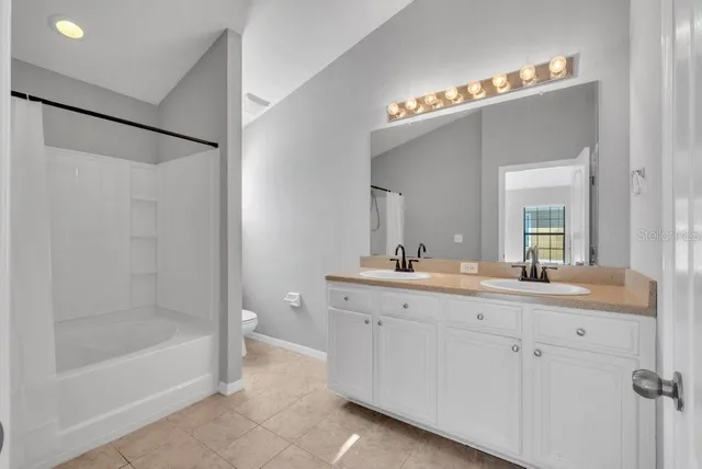 a bathroom with a bathtub a double vanity sink and mirror