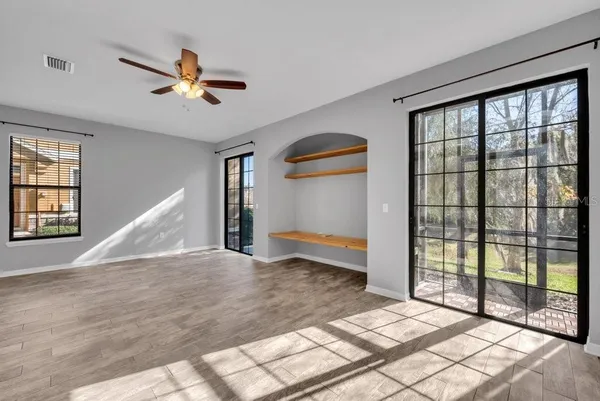 a view of empty room with wooden floor and fan