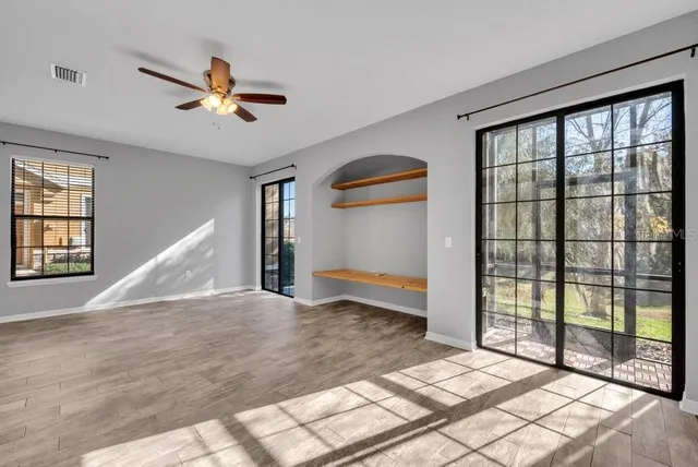 a view of empty room with wooden floor and fan