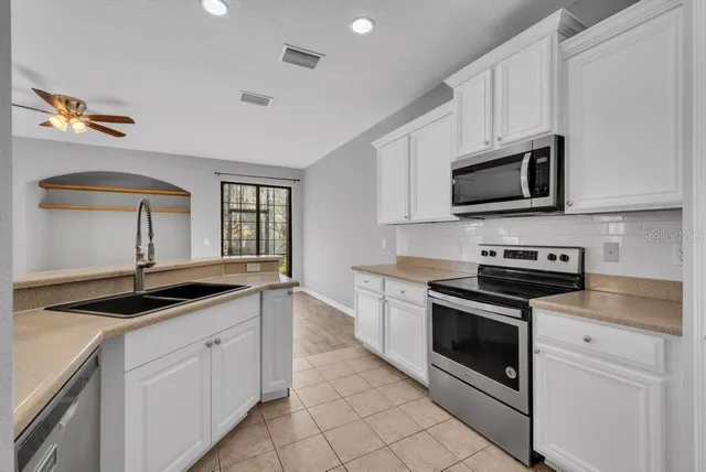 a kitchen with granite countertop a sink stainless steel appliances and cabinets