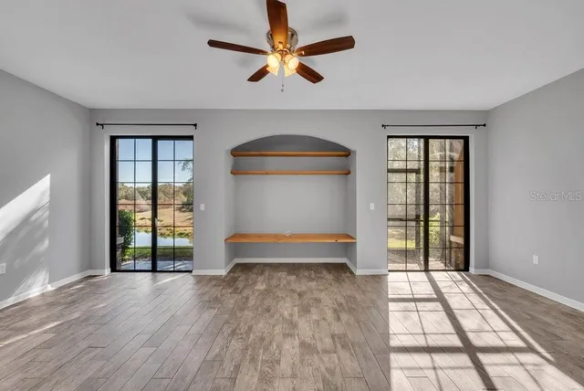 an empty room with windows and ceiling fan