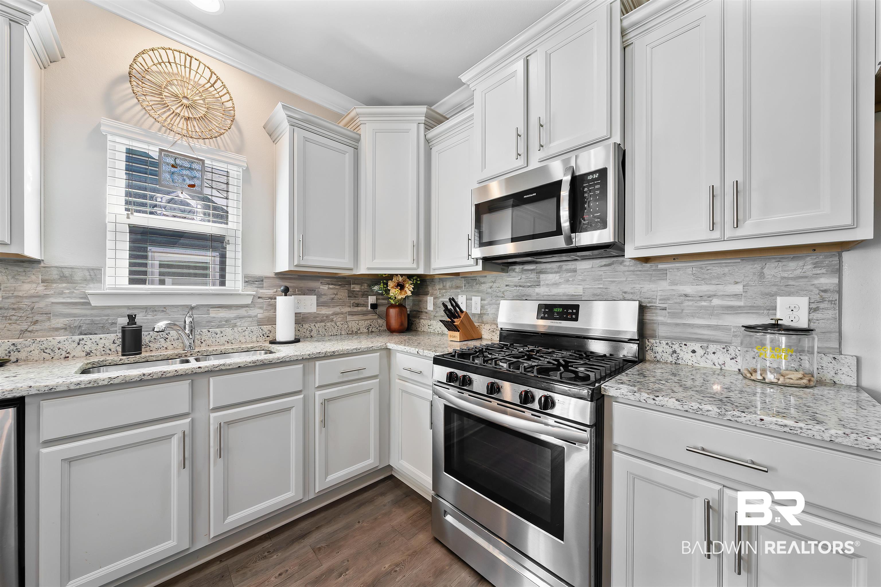 1221 Primrose Lane Foley, AL 36535 - Photo 25 of 29 Kitchen with a sink, appliances with stainless steel finishes, white cabinets, decorative backsplash, and dark wood-style flooring