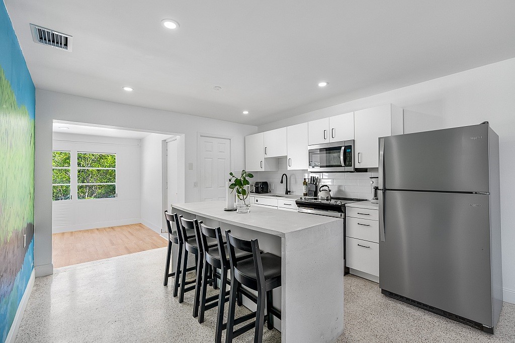 30 Southwest Hideaway Place Stuart, FL 34994 - Photo 3 of 35 a kitchen with stainless steel appliances a refrigerator a stove a sink dishwasher a dining table and chairs with wooden floor