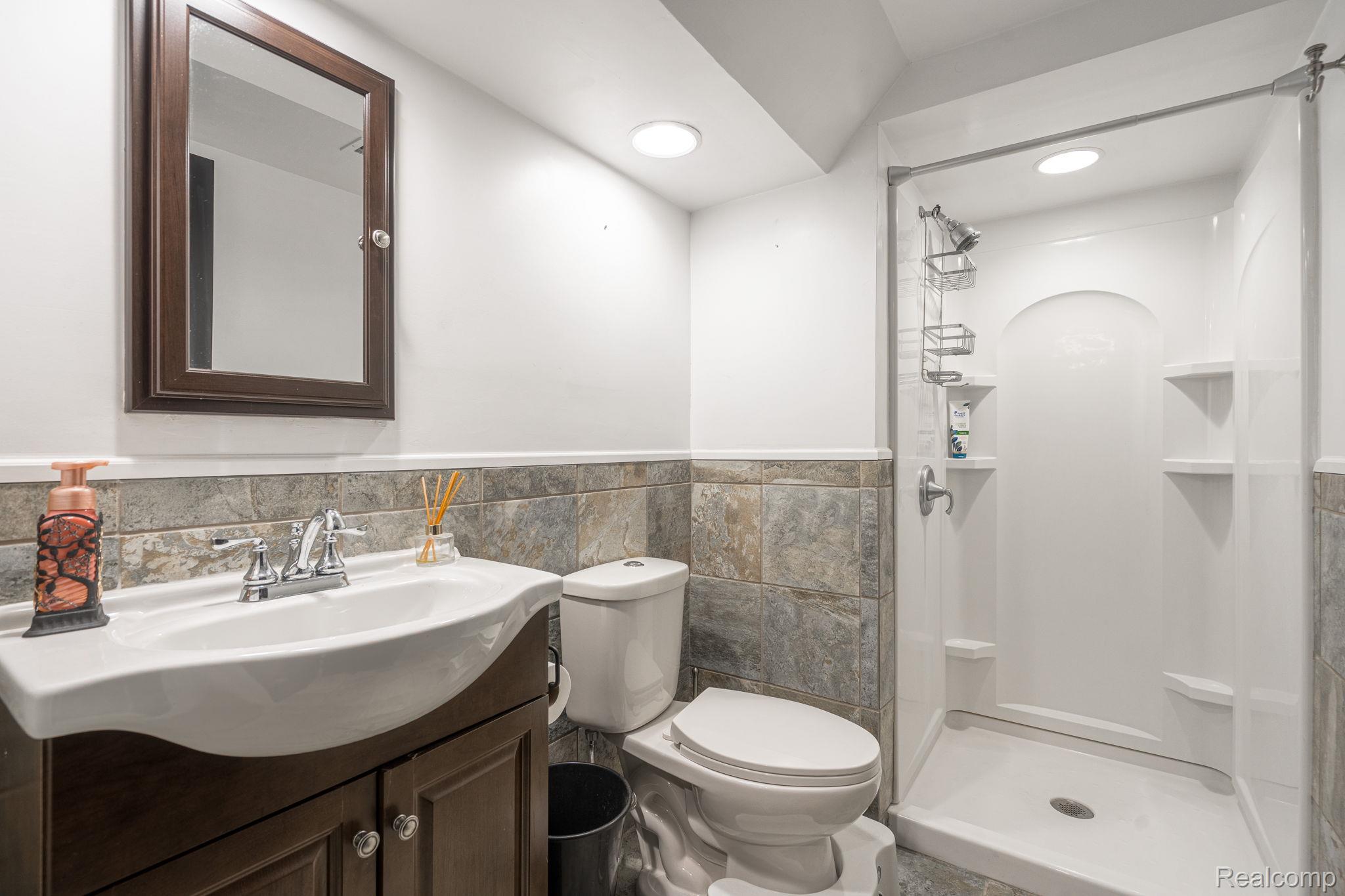 6803 Napoleon Road Jackson, MI 49201 - Photo 52 of 59 Bathroom featuring vanity, a shower stall, tile walls, wainscoting, and recessed lighting