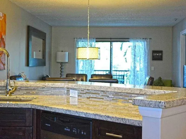 a view of a kitchen with kitchen island a sink a counter top space and living room area