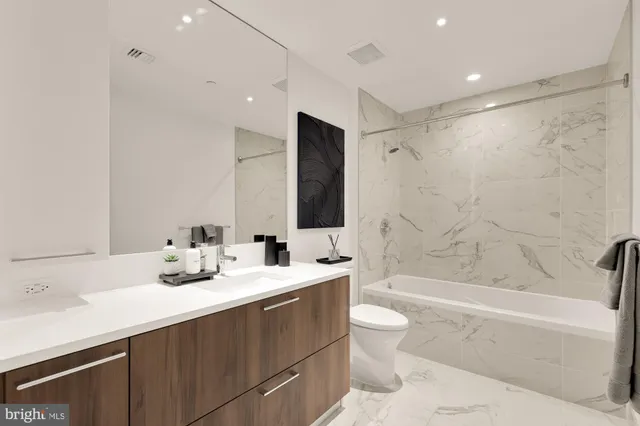 a bathroom with a double vanity sink toilet mirror and bathtub