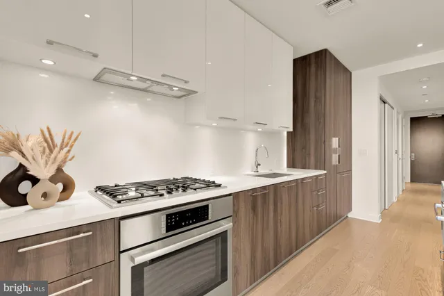 a kitchen with stainless steel appliances a stove a sink dishwasher and a refrigerator with wooden floor