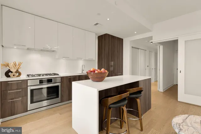 a kitchen with stainless steel appliances kitchen island a table chairs in it and white cabinets
