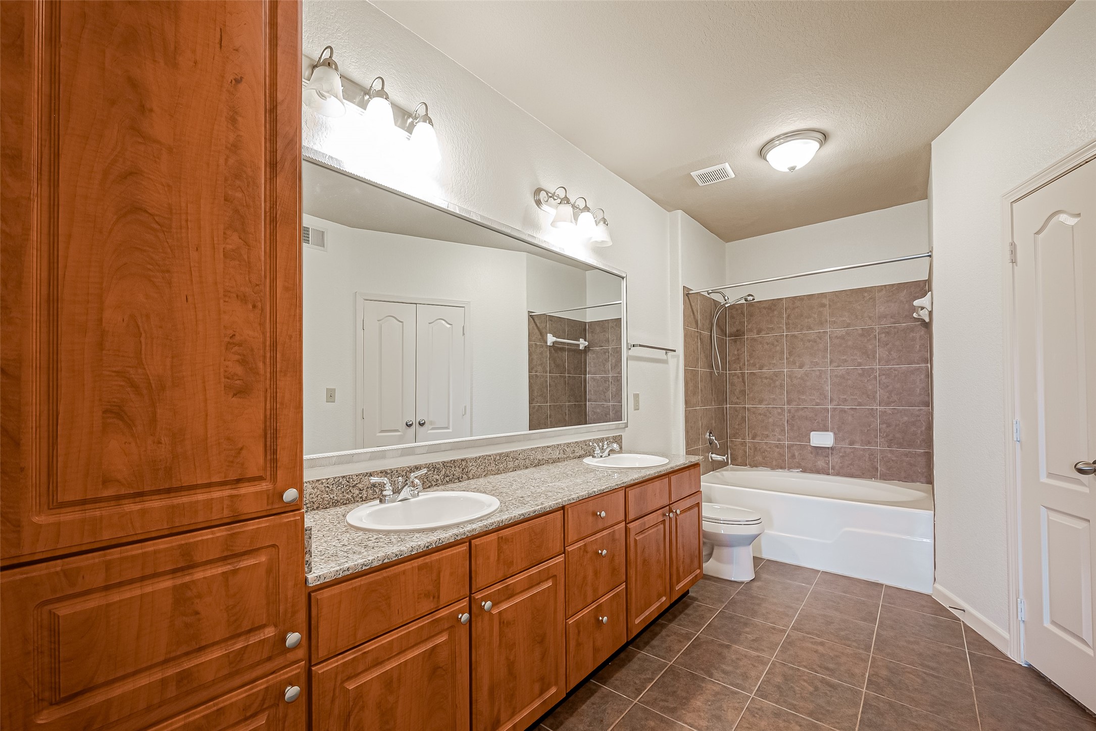 1711 Old Spanish Trail, Unit 303 Houston, TX 77054 - Photo 27 of 37 a bathroom with a double vanity sink a large mirror and a bathtub