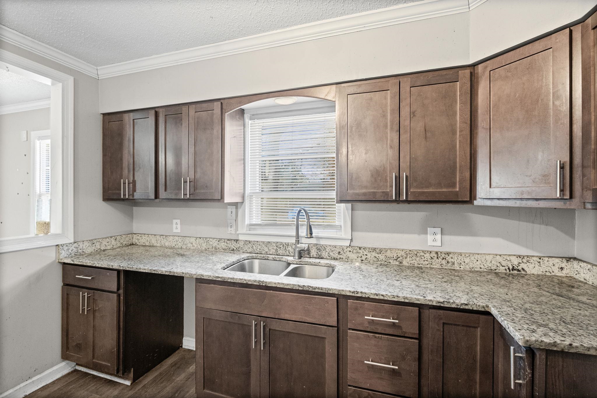 4202 Reed Avenue Memphis, TN 38108 - Photo 11 of 22 Kitchen featuring dark brown cabinets, light stone countertops, ornamental molding, a textured ceiling, and dark wood-type flooring
