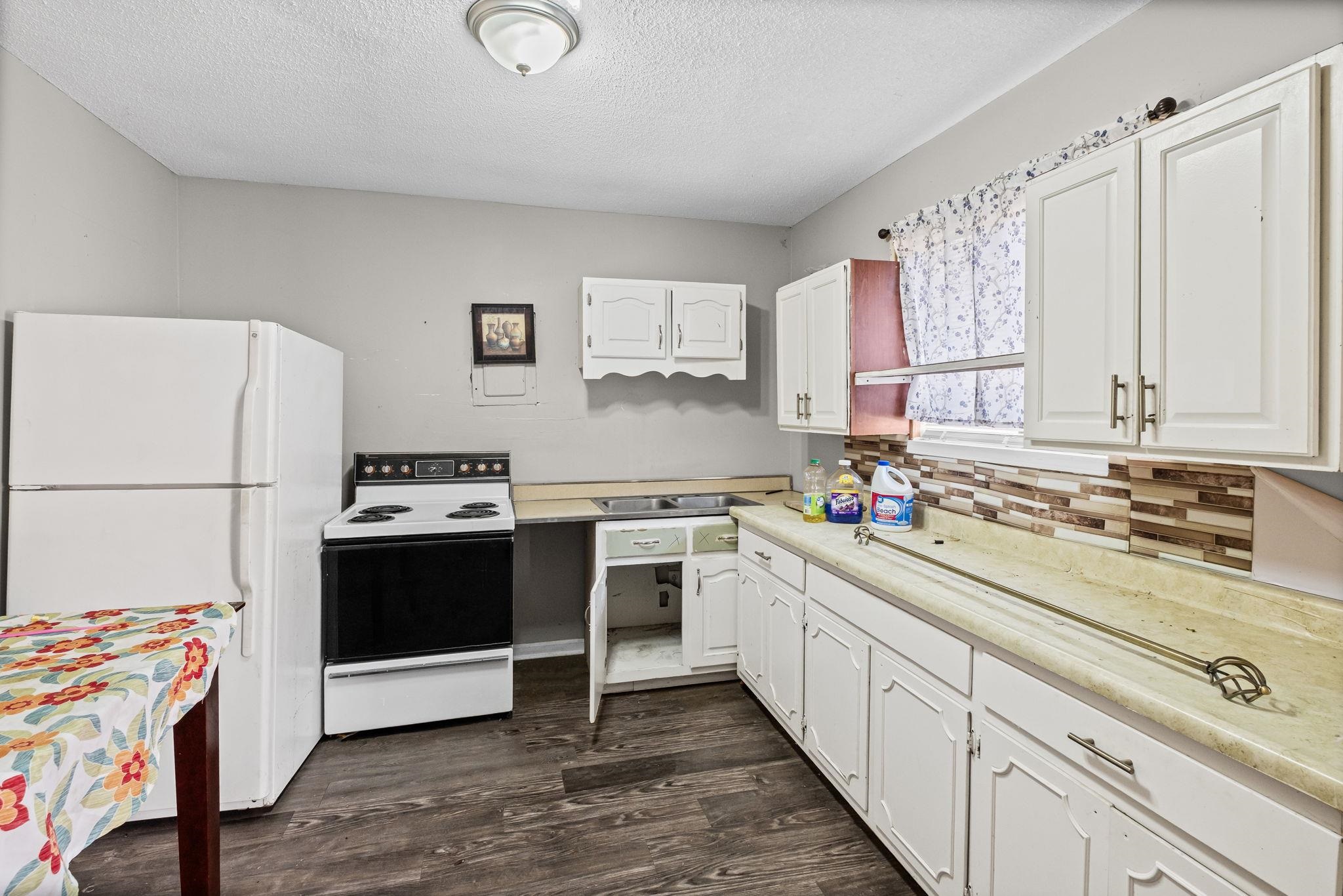 4202 Reed Avenue Memphis, TN 38108 - Photo 15 of 22 Kitchen featuring white appliances, light countertops, a textured ceiling, white cabinets, and dark wood finished floors