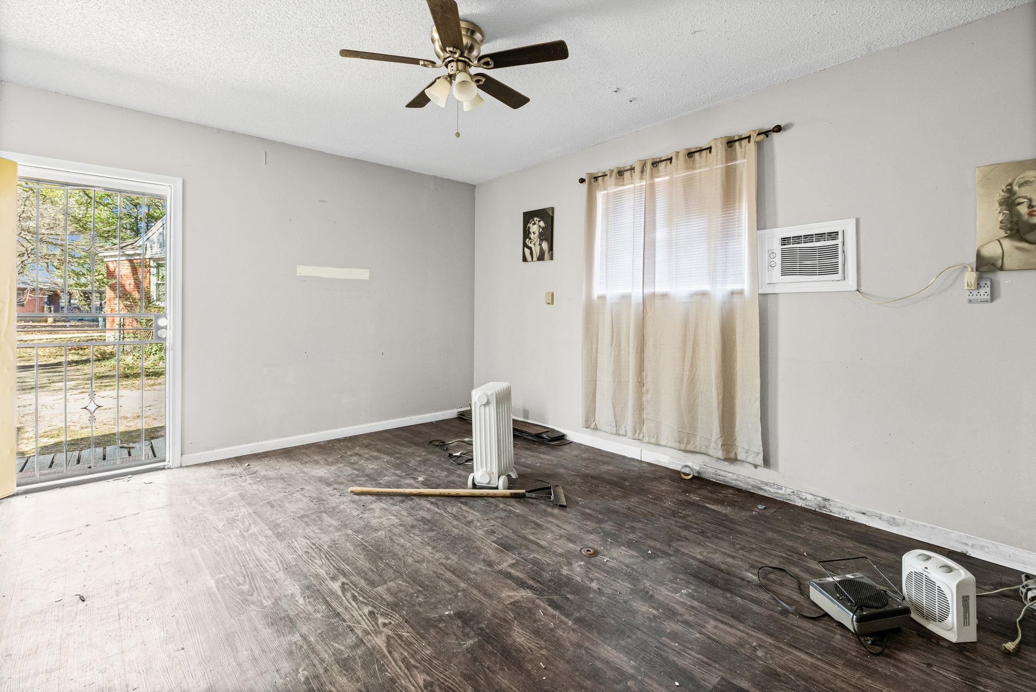 4202 Reed Avenue Memphis, TN 38108 - Photo 16 of 22 Unfurnished room featuring a textured ceiling, wood finished floors, ceiling fan, radiator, and a wall mounted air conditioner