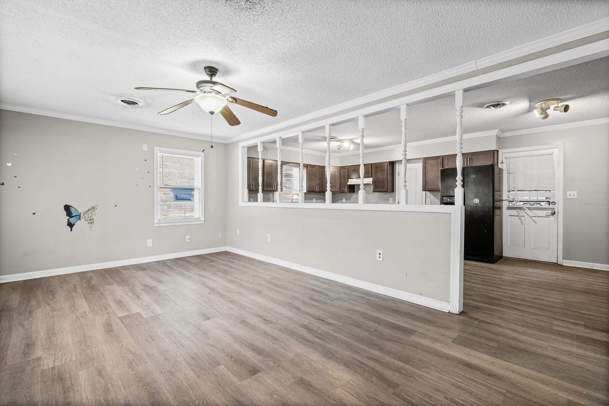 4202 Reed Avenue Memphis, TN 38108 - Photo 5 of 22 Unfurnished living room with ornamental molding, a textured ceiling, dark wood-style floors, and ceiling fan