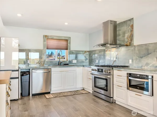 a kitchen with granite countertop white cabinets and stainless steel appliances