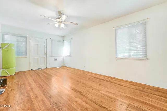 a view of an empty room with wooden floor and a window
