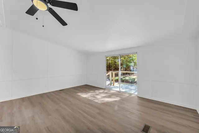 an empty room with wooden floor fan and windows