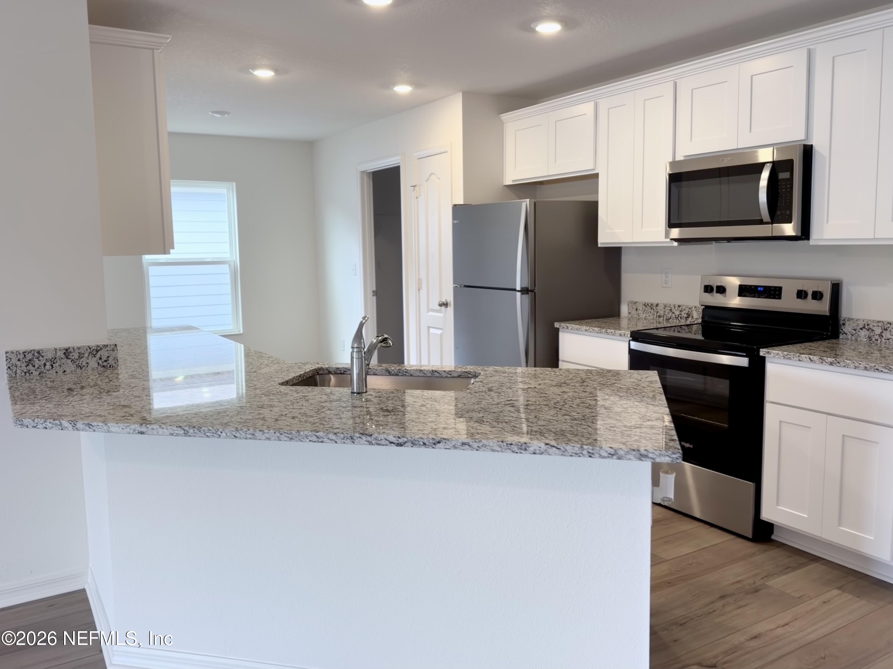 37397 Whisper Way Hilliard, FL 32046 - Photo 4 of 9 a kitchen with stainless steel appliances granite countertop a refrigerator a stove a sink and a granite counter tops
