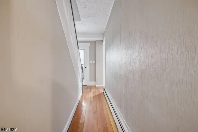 a view of a hallway with wooden floor and a white door