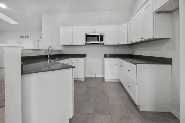 a kitchen with granite countertop white cabinets and a stainless steel appliances