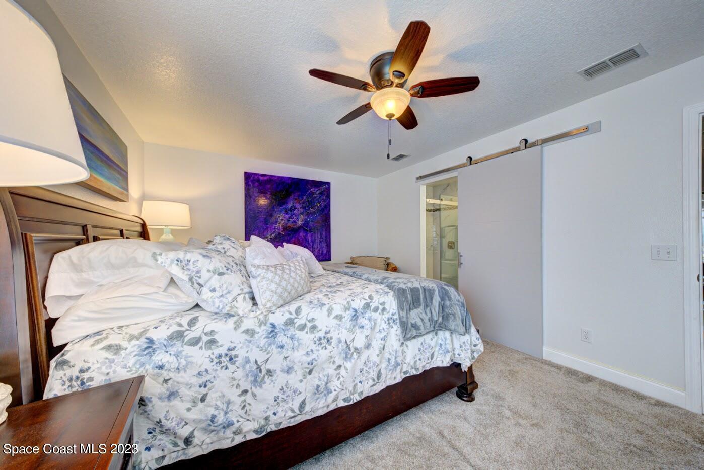 2760 Revolution Street, Unit 103 Melbourne, FL 32935 - Photo 24 of 40 a bedroom with a large bed and a chandelier
