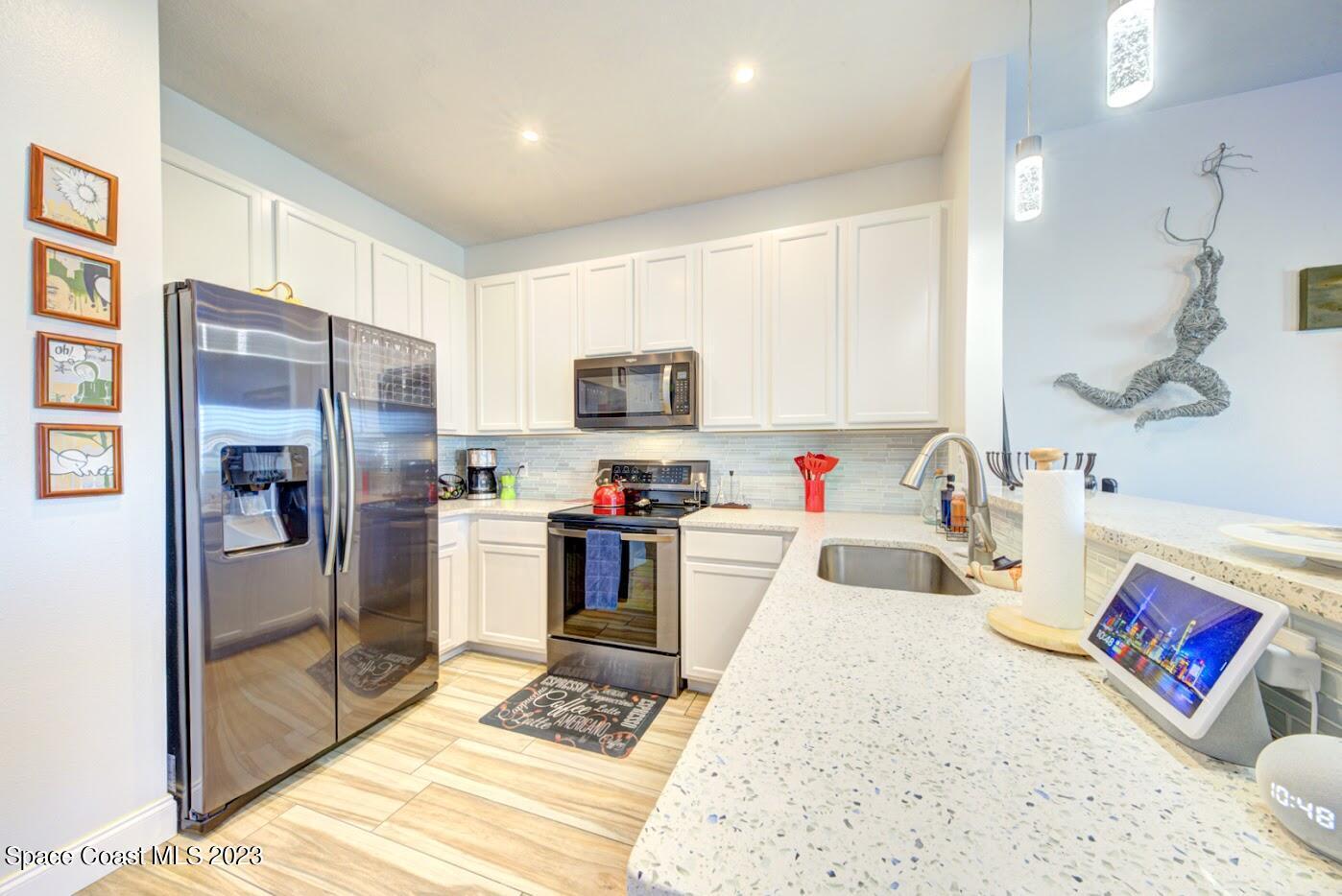 2760 Revolution Street, Unit 103 Melbourne, FL 32935 - Photo 7 of 40 a kitchen with stainless steel appliances kitchen island granite countertop a refrigerator sink and stove