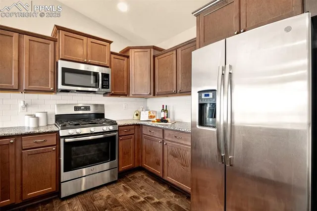 a kitchen with stainless steel appliances granite countertop a stove a refrigerator and a microwave
