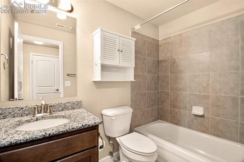 4293 Hessite Loop Colorado Springs, CO 80938 - Photo 28 of 37 a bathroom with a granite countertop toilet a sink and a bathtub