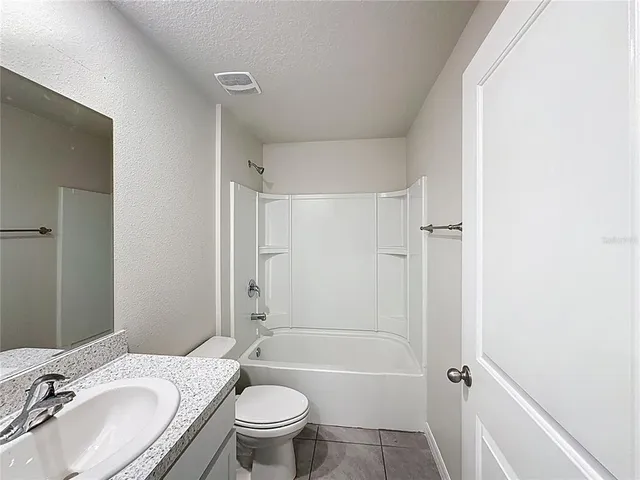 a bathroom with a granite countertop sink toilet mirror and shower