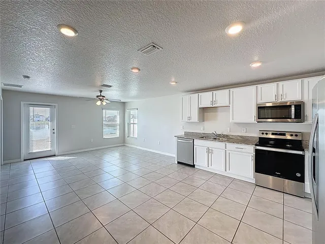a large kitchen with granite countertop a stove a sink dishwasher and a refrigerator