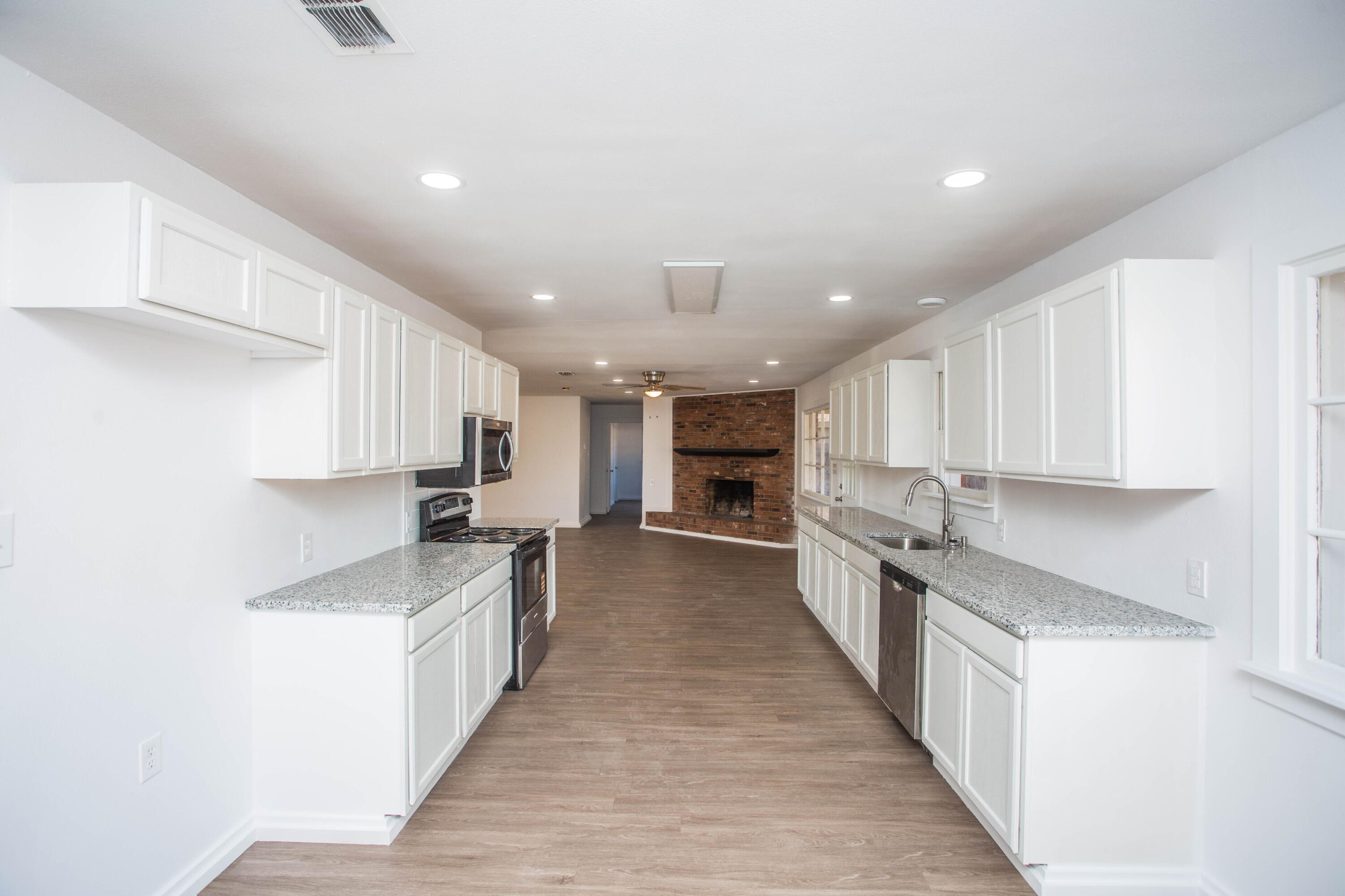 6004 Vernon Avenue Lubbock, TX 79412 - Photo 14 of 34 a large kitchen with stainless steel appliances lots of counter space and wooden floor