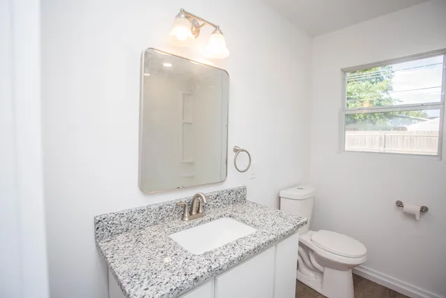 a bathroom with a granite countertop sink a toilet and a mirror