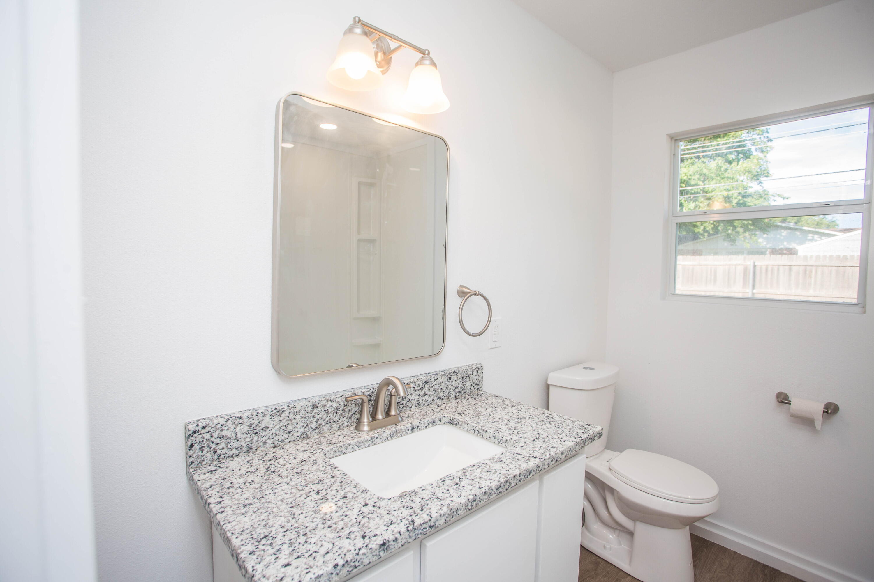 6004 Vernon Avenue Lubbock, TX 79412 - Photo 21 of 34 a bathroom with a granite countertop sink a toilet and a mirror