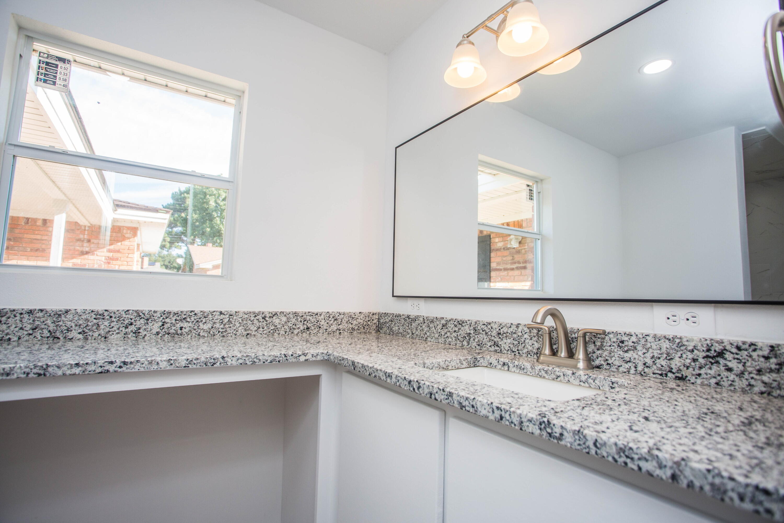 6004 Vernon Avenue Lubbock, TX 79412 - Photo 27 of 34 a bathroom with a granite countertop sink mirror and a window