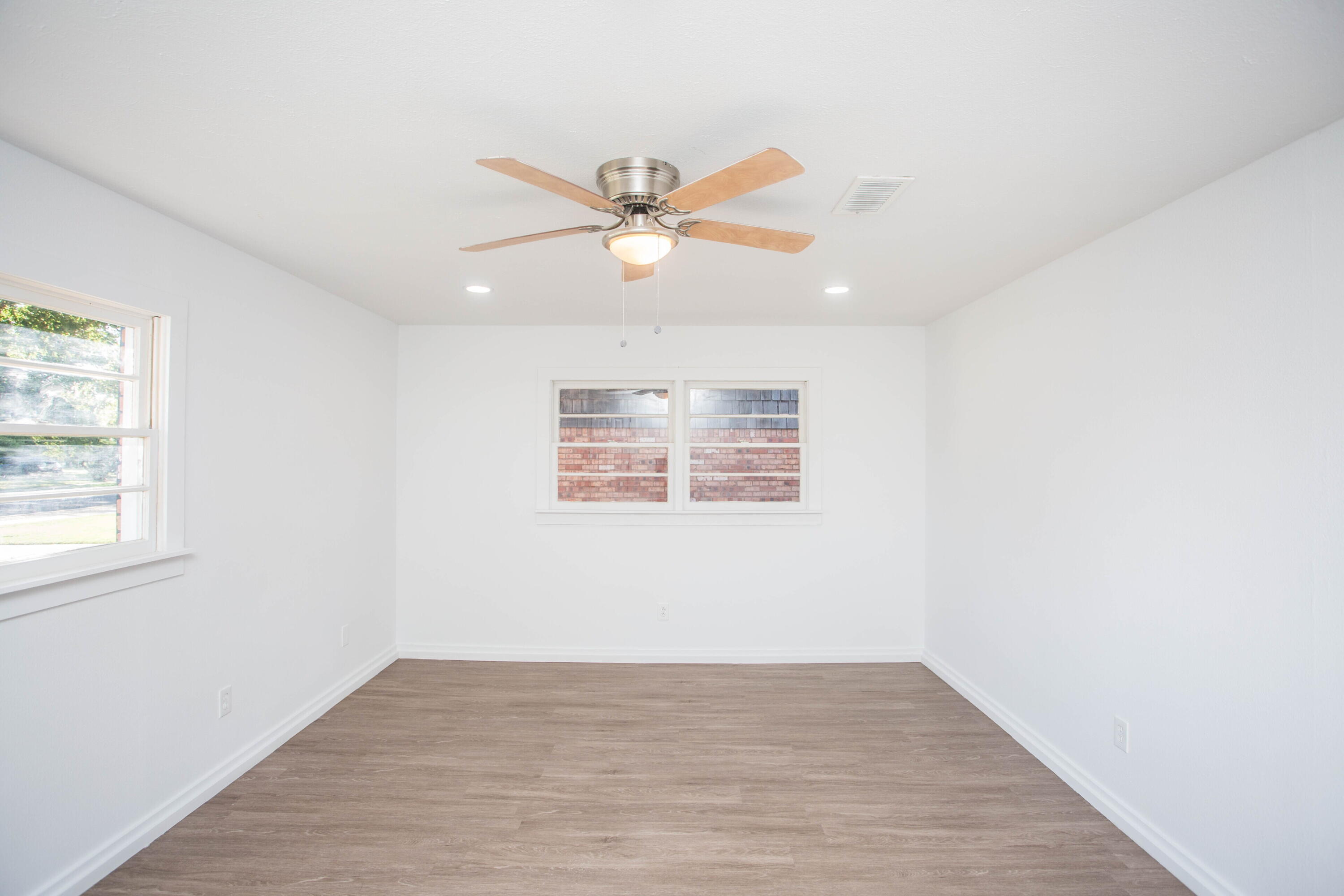 6004 Vernon Avenue Lubbock, TX 79412 - Photo 30 of 34 an empty room with wooden floor fan and windows