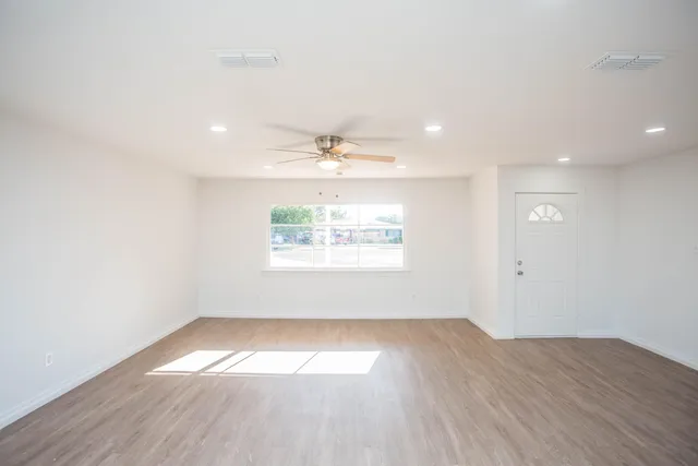an empty room with wooden floor and windows