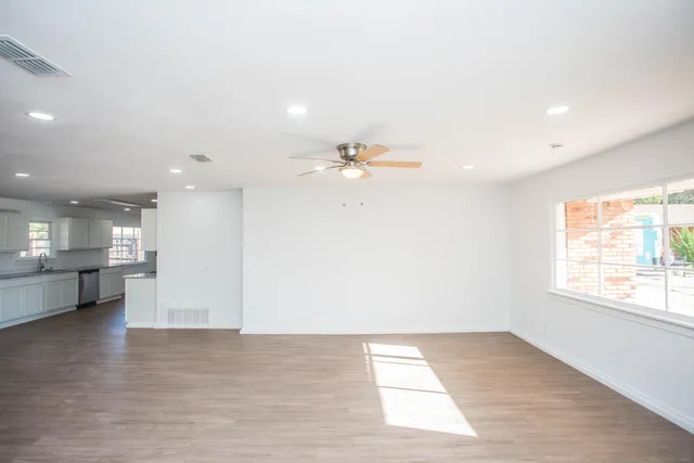 a view of empty room with kitchen and window