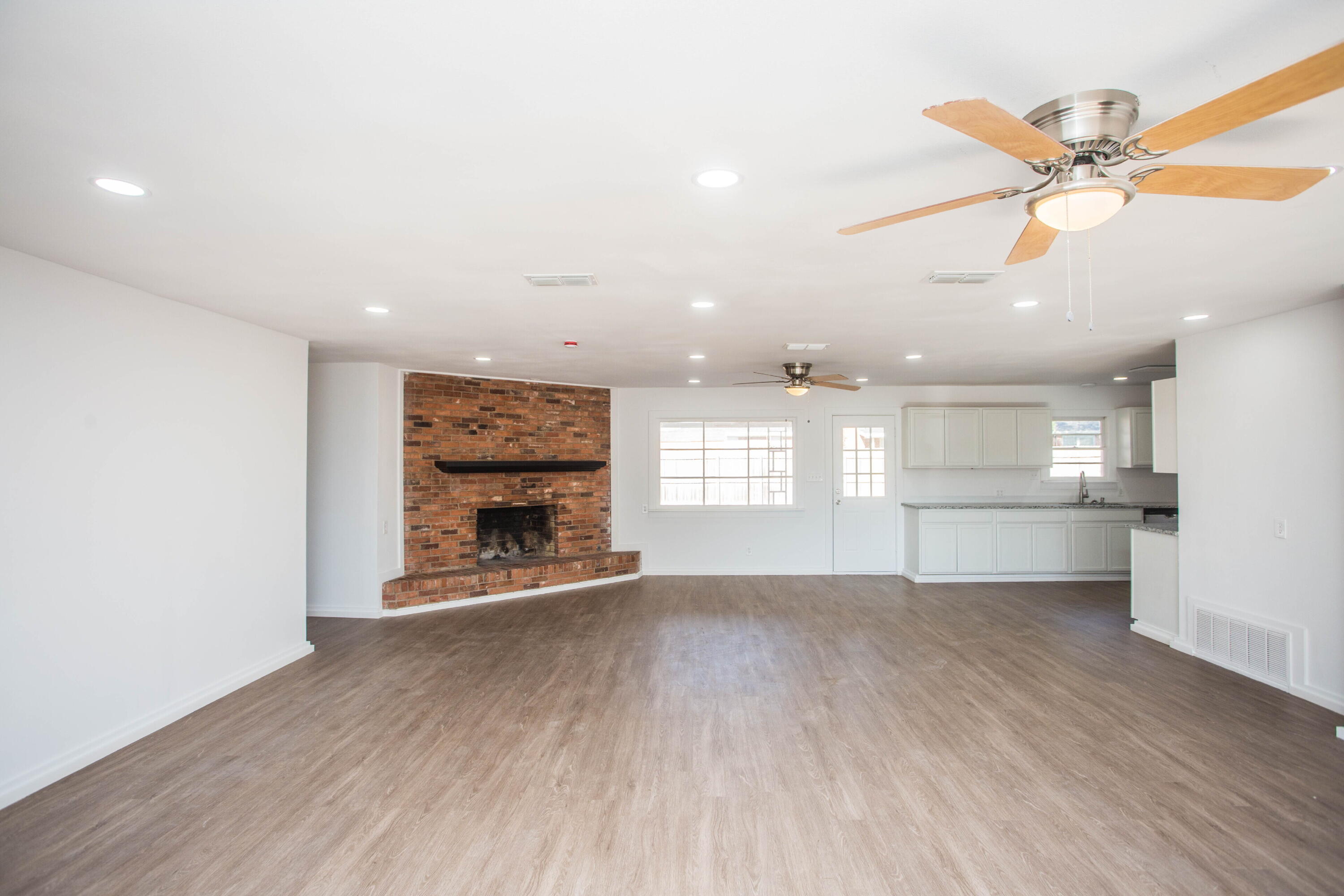 6004 Vernon Avenue Lubbock, TX 79412 - Photo 5 of 34 an empty room with wooden floor a ceiling fan and windows