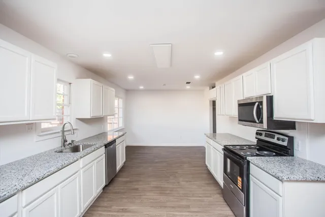 a large kitchen with stainless steel appliances granite countertop a sink stove and refrigerator