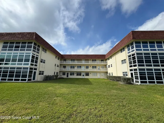 a view of a house with a big yard and large trees