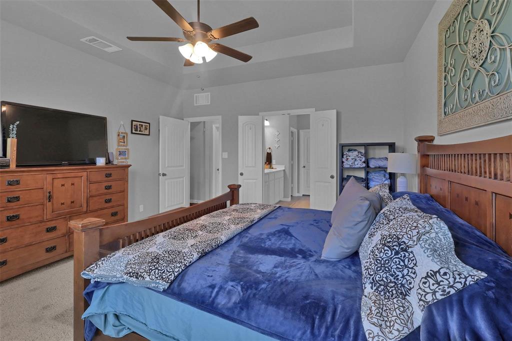 154 Chester Road Springtown, TX 76082 - Photo 13 of 40 a bed room with a bed and a flat tv screen on a dresser