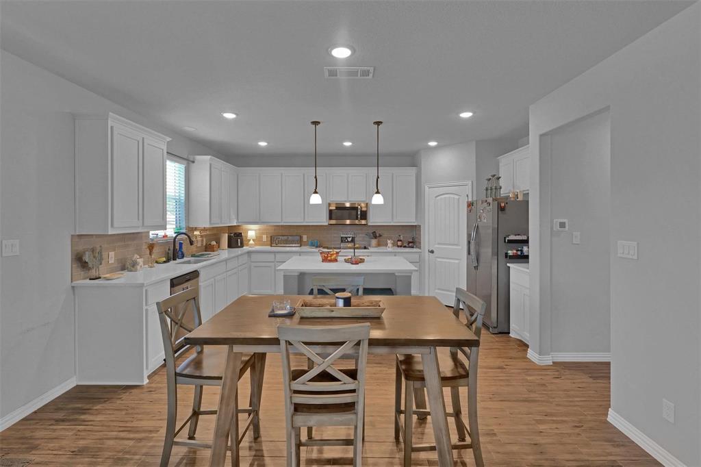 154 Chester Road Springtown, TX 76082 - Photo 9 of 40 a kitchen with a dining table chairs refrigerator and cabinets