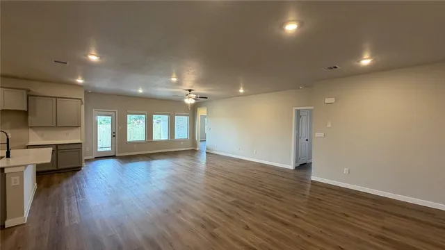 an empty room with wooden floor fan and windows