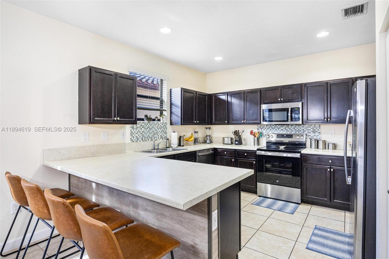 415 Southeast 34th Terrace Homestead, FL 33033 - Photo 8 of 60 a kitchen with granite countertop a stove top oven a sink dishwasher a dining table and chairs