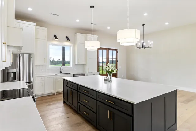 a large kitchen with a center island wooden floor stainless steel appliances and cabinets