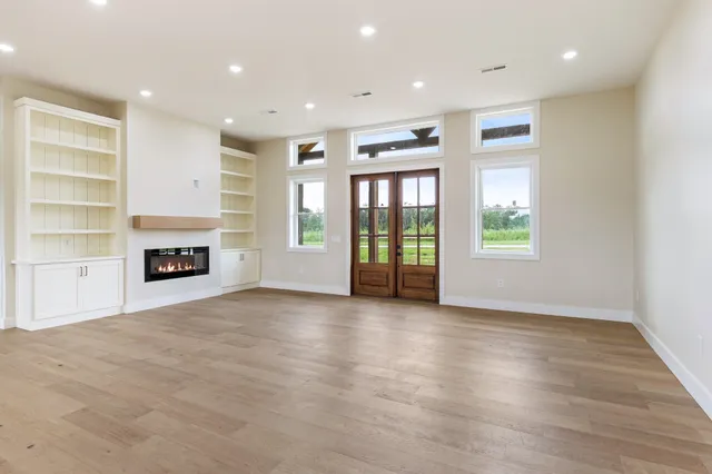 an empty room with windows and fireplace